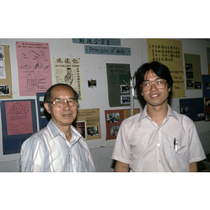 Henry Wong stands with another man by an information board at the Chinese Progressive Association office