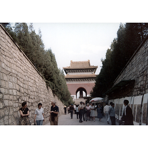 Men and women stand in a walkway bordered by high stone walls