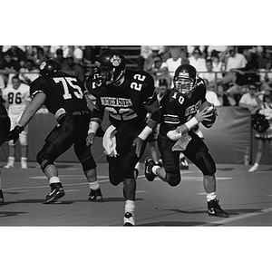 Three Northeastern football players in action on the field during a game