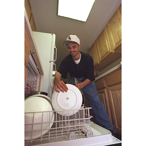 Young man loading dishwasher in a residence hall suite