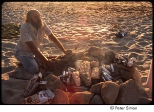 Ram Dass cooking fish and corn over an open fire on the beach