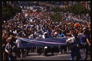 Massive crowd marching in the San Francisco Pride Parade, carrying banner reading 'Mayors contingent': Art Agnos waving to the crowd from the back of an automobile