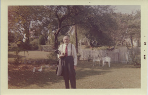 W. E. B. Du Bois standing outside in an unidentified yard holding his jacket