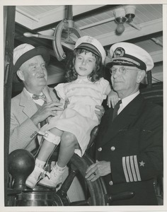 President Bruce Barton and ship captain show little girl how to steer