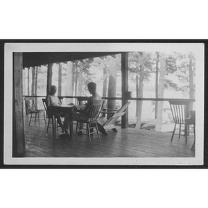 Two people seated at table in a porch