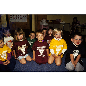 Children wearing West Roxbury-Roslindale YMCA shirts seated on a classroom floor