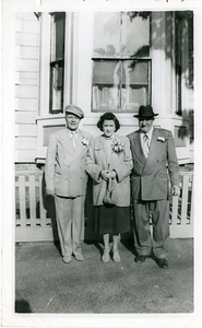 Manny Dias posing with couple in front of house