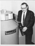 Suffolk University Dean Michael R. Ronayne (CAS, 1972-2004) poses with a Gammacell 220, a self-contained research irradiator, photograph, circa 1970s