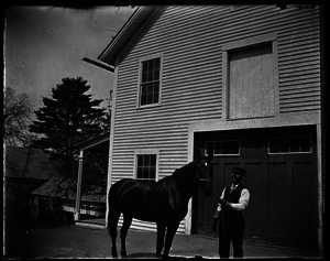 Groomsman and horse in front of a barn