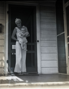 Mrs. Riker standing in a doorway with infant Elmer