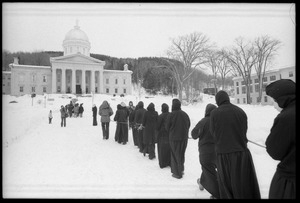 Protesters from Bread and Puppet Theater, dressed in cloaks and masks, unfurl a banner or puppet during a demonstration against the invasion of Laos at the Vermont State House