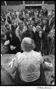 Ram Dass seated on stage at the College of Marin, talking to audience members