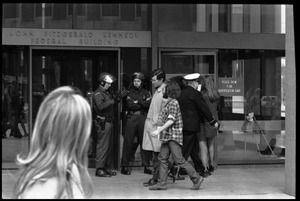 Police at the entrance to the John F. Kennedy Federal Building, with antiwar protesters picketing