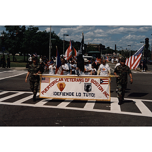 Two men in military fatigues carry a banner for the Puerto Rican Veterans of Boston at the Festival Puertorriqueño