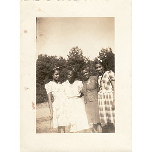 Four women pose in a sandy lot