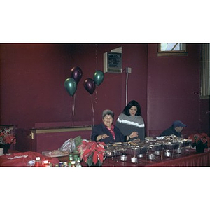 Inquilinos Boricuas en Acción staffer Carmen Colombani and another woman preside over the food table at a Three Kings Day celebration.