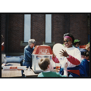 A woman holds a white balloon as a boy grasps a string tied to it at the Boys and Girls Clubs of Boston 100th Anniversary Celebration Street Fair