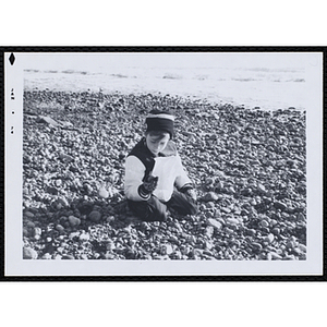 A boy picks-up stones on a beach