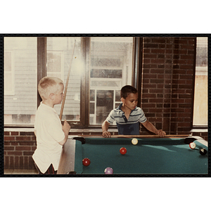 Two boys playing a game of pool