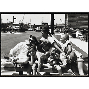 A Counselor poses with a group of kids sitting on a bench at the pier
