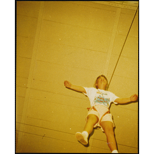 A girl on a safety rope holds out her arms in the air