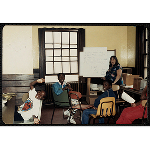 A Group of three students smile as an unidentified woman teaches a lesson