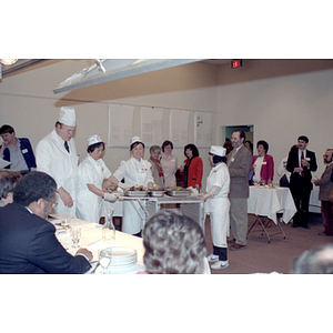 Chefs prepare food standing in front of judges and onlookers