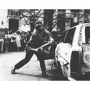 A student takes a sledge hammer to a car during the Interfraternity Car Smashing