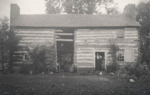 Log farmhouse with man and woman inside doorway