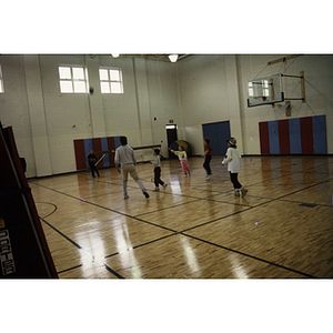 One adult and group of children play a game in a gymnasium