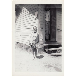 A young boy poses outside a cabin at Breezy Meadows Camp