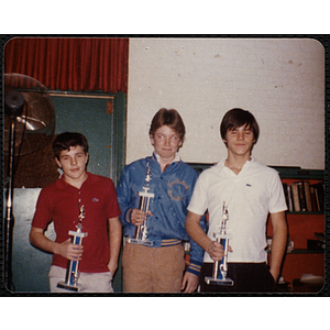 Three Boys' Club members posing with their sports trophies