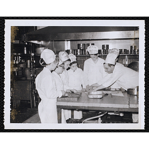 Members of the Tom Pappas Chefs' Club work with a chef in a kitchen