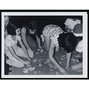 Girls assemble a jigsaw puzzle on a floor mat