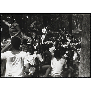 A group of children raise their hands in the woods