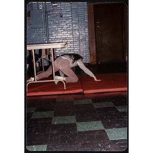 A girl crawls under a table at the Charlestown gymnasium