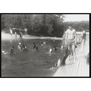 A swimming supervisor watches two boys on a dock