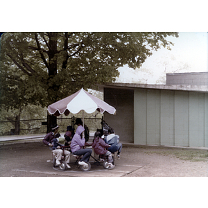 Children play on a merry-go-round during a tutoring class picnic