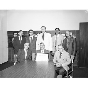 Group of men surrounding Charles T. Cobb and his certificate of appreciation from NU