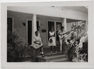 White civil rights worker playing guitar on the front steps of the Freedom House (Kathy Dahl, far right)