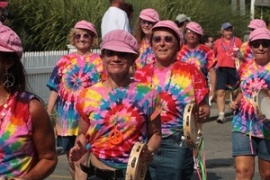 Parade marchers in tie-dye shirts and pink hats : Provincetown Carnival parade