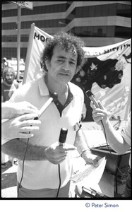 Unidentified man wearing a Mobilization for Survival button talking to the media at an antinuclear demonstration near Draper Laboratory, MIT