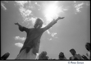 Bhagavan Das dancing with arms raised at Sonoma State University, silhouetted against the sun