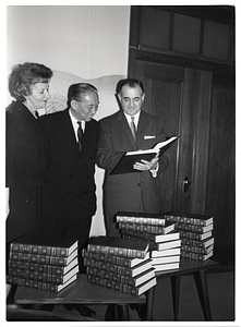 Unidentified woman and two unidentified men with stacks of books