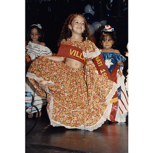 A young girl in a dress and a sash at the Festival Puertorriqueño