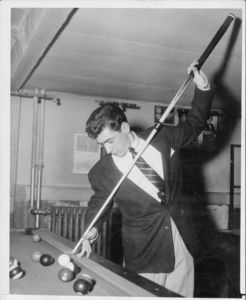 Joseph Saponaro Jr., a member of Suffolk University's billiards team, achieves the title of 1957 Intercollegiate Pocket Billiards National Champ; pictured with pool cue in hands