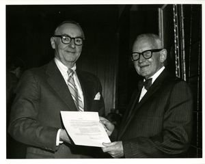 Suffolk University President Thomas A. Fulham (1970-1980) presents a resolution to Professor John O'Brien at O'Brien's retirement party