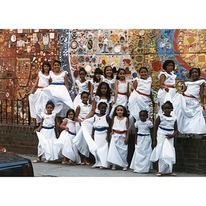Seventeen girls pose for a group portrait in front of the ceramic tile mural in Plaza Betances.