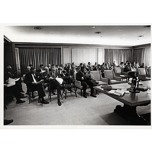 Board members, seated in chairs, review documents during a Boys' Club meeting