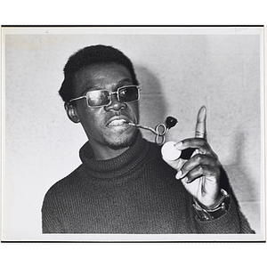 A male staff member from the Boys' Clubs of Boston, smoking a pipe and holding a table tennis ball